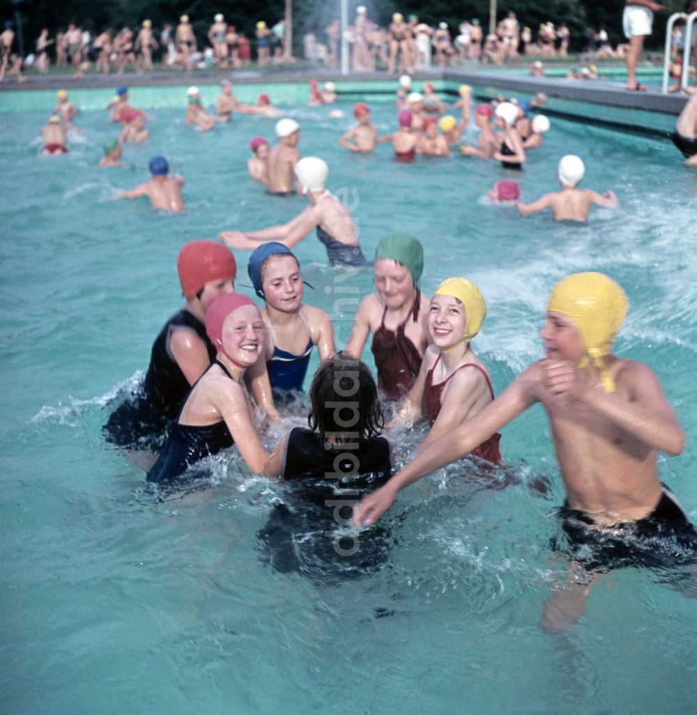 Berlin: Mädchen in Badeanzügen und mit Badekappen und Schwimmring in einem Freibad in Berlin in der DDR